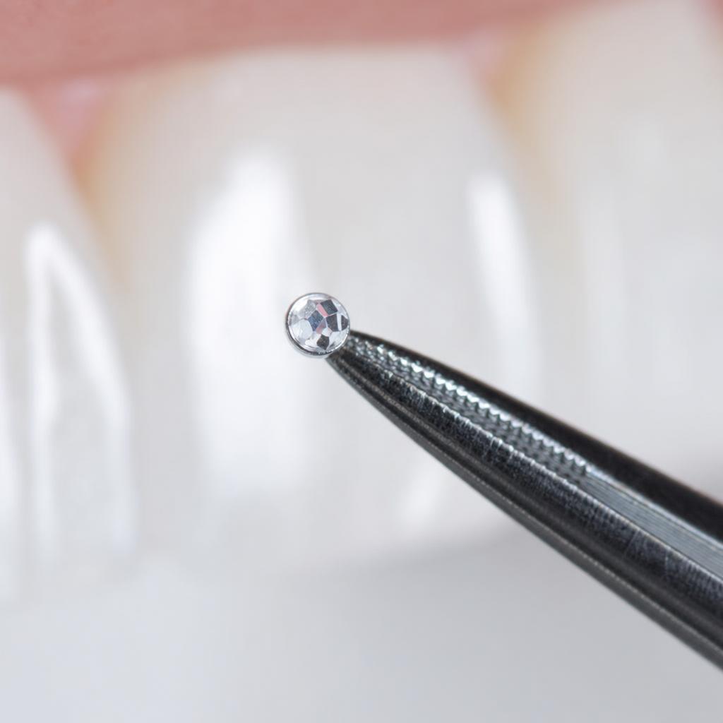 Swarovski Kristall auf Dental-Pinzette vor einem Zahn